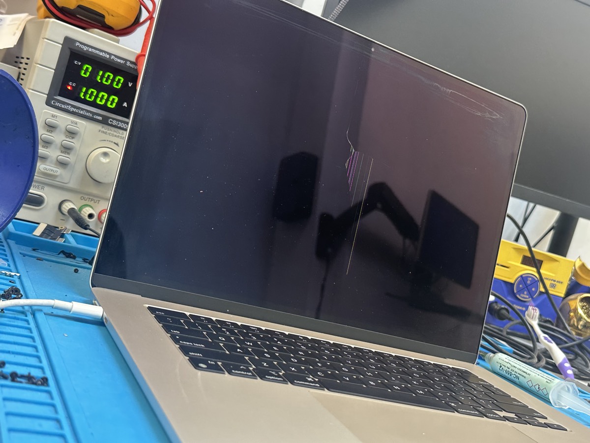 Cracked MacBook Pro screen with vertical line damage on repair bench at The Mac Space