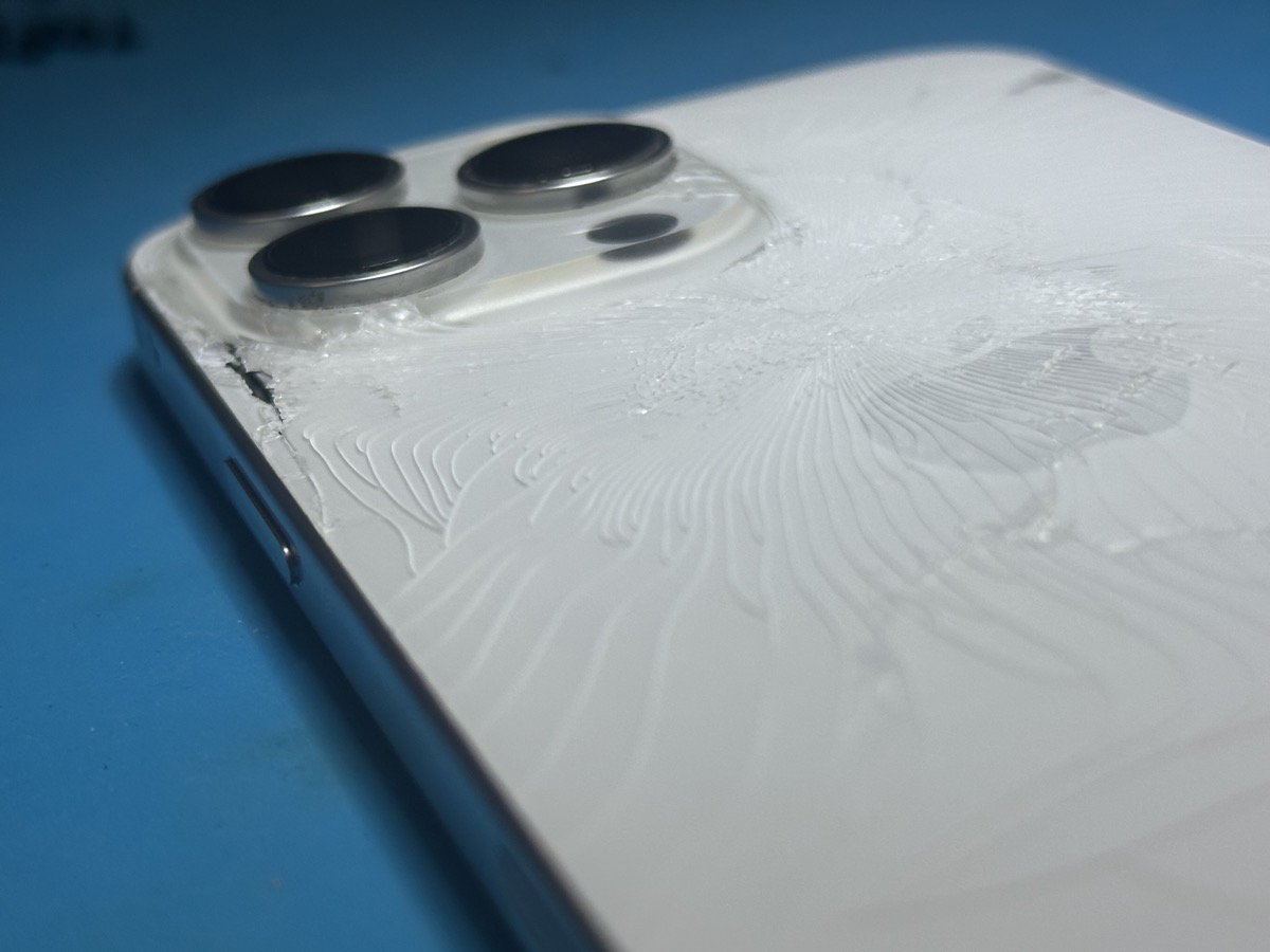 Close-up of shattered iPhone 16 Pro Max back glass near triple camera system