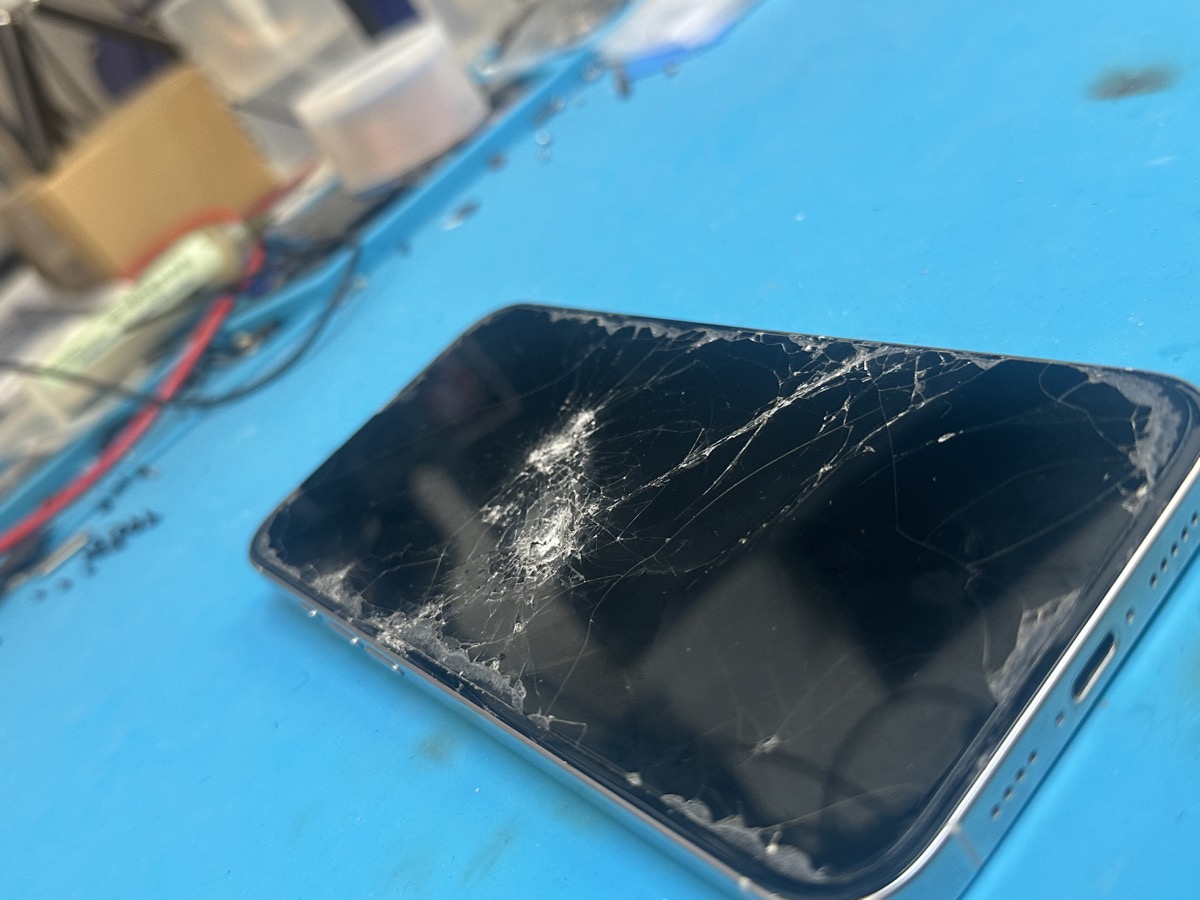 iPhone 16 Pro Max with completely shattered front screen at The Mac Space repair shop